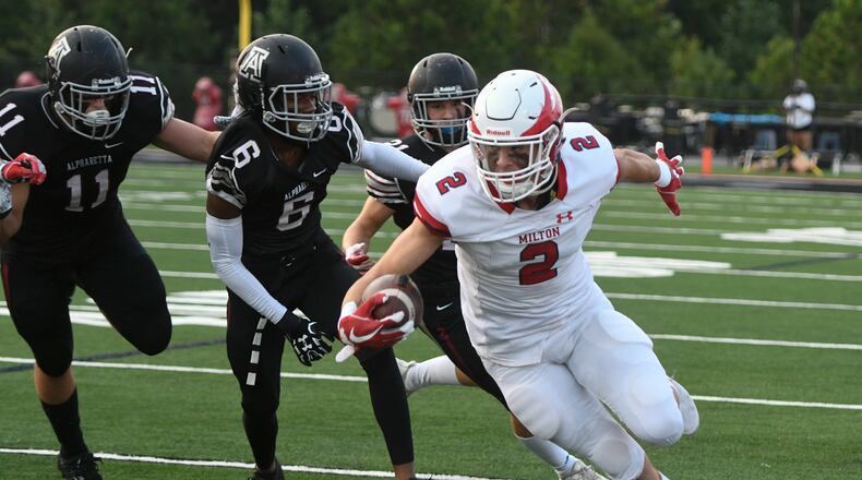 Milton WR Dylan Leonard (2) runs against the defense of Jackson Michaels (11) and Jared Rumph (6) during high school football featuring Milton at Alpharetta on Friday, Aug. 24, 2018.