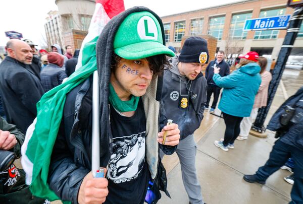 A man wearing a Luigi hat is escorted away as people arrive for a town hall with Elon Musk, Sunday, March 30, 2025, in Green Bay, Wis. (AP Photo/Jeffrey Phelps)
