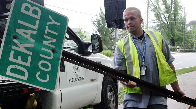 A Dunwoody Public Works employee carries an old Dekalb County sign to his truck after replacing it with the City of Dunwoody's first city limit sign in 2009.