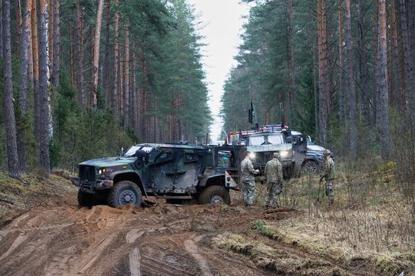 U.S. soldiers stand near military vehicles parked at a training range in Pabrade, north of the capital Vilnius, Lithuania on Thursday, March 27, 2025. (AP Photo/Mindaugas Kulbis)