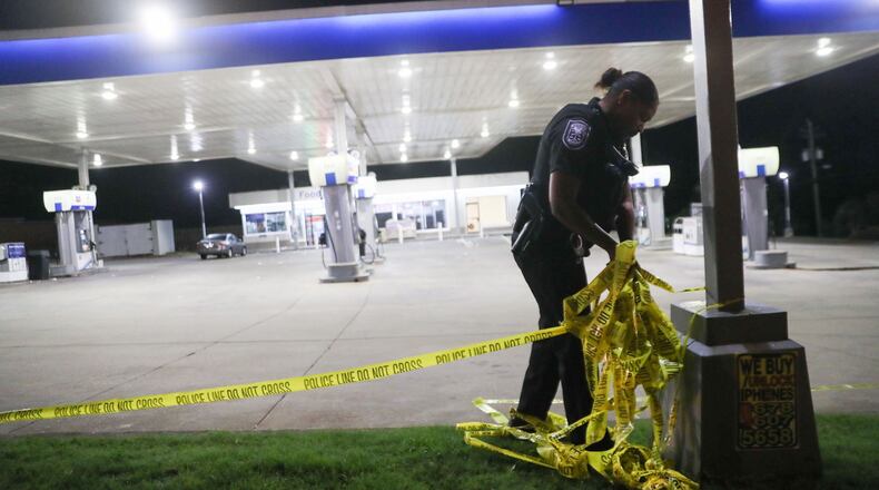 A DeKalb County police officer collects crime scene tape from a Chevron on Candler Road, where Channel 2 Action News reported a man wan killed Wednesday morning when he tried to intervene in a couple's fight.