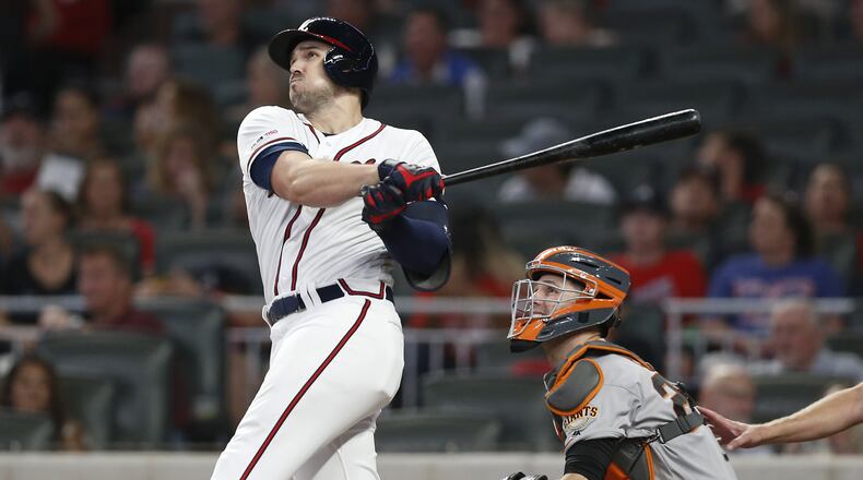 The Braves’ Adam Duvall hits a two-run homer in the seventh inning while Giants catcher Buster Posey looks on during Saturday’s game at SunTrust Park.