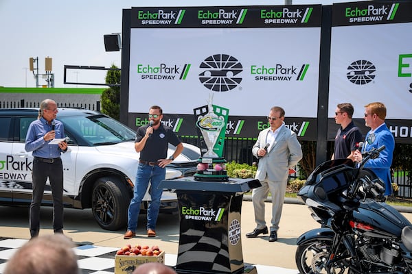Dignitaries and drivers discuss the newly named EchoPark Speedway (formerly Atlanta Motor Speedway) and added perks for the winner of this month's Quaker State 400 NASCAR Cup Series race, with the victor set to receive a “nearly new” EchoPark Chevy Silverado and a trailer equipped with an 85th Anniversary, Sturgis Motorcyle Rally Limited Edition Harley-Davidson motorcycle. From left to right: Kyle Petty, former Cup Series driver; Ross Chastain, current Cup Series driver; David B. Smith, chairman and CEO of Sonic Automotive; Christopher Bell, current Cup Series driver and winner of the Ambetter 400 race at AMS in February; and Brandon Hutchison, executive vice president and general manager of EchoPark Speedway. Sonic Automotive owns EchoPark Automotive. (Courtesy of EchoPark Speedway)