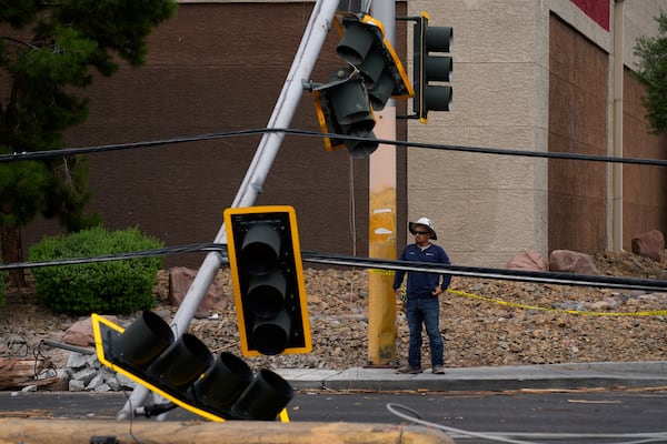 A worker stands beside traffic lights damaged in a storm Wednesday, July 2, 2025, in Las Vegas. (AP Photo/John Locher)