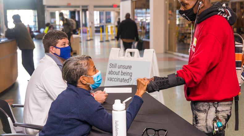 Grady Hospital staffs a vaccine question desk in the main lobby of the hospital Tuesday, Oct 19, 2021, with Emory senior resident Dr. Billy Joe Mullinax, seated back left, and professor Dr. Kimberly Manning, seated front. The doctors are available in the 'no judgement zone' for anyone with concerns or questions still looking for information on the COVID vaccinations. Minnette Hardeman, right, who isn’t vaccinated, talks with Manning and says, “I’m afraid of it.  I’ve never had nobody to sit down and talk about these things.” The desk is open mi day on Tuesdays and Thursdays. (Jenni Girtman for The Atlanta Journal-Constitution)