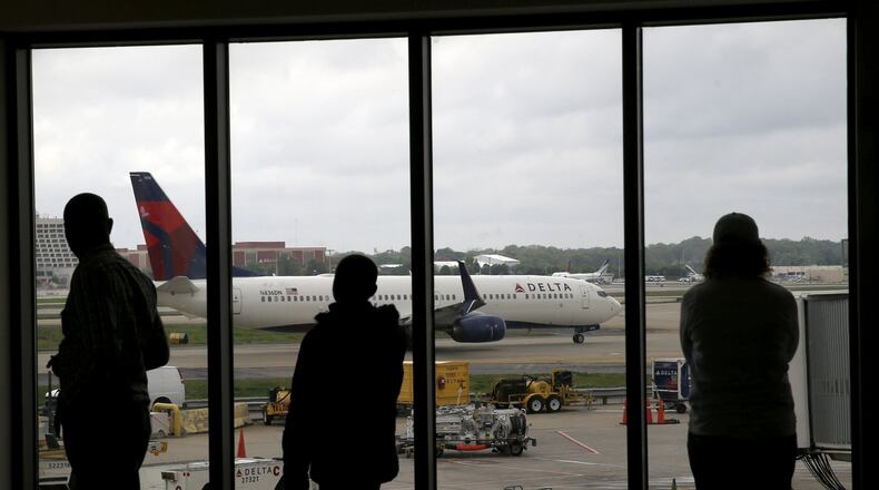 Delta Air Lines passengers watch as a Delta plane taxis at Hartsfield-Jackson. (AP Photo/Charles Rex Arbogast, File)