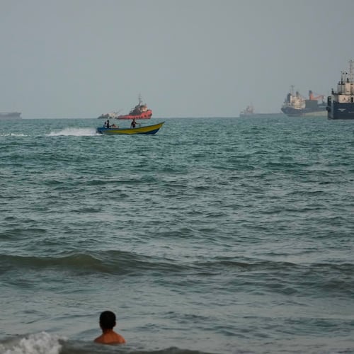 A swimmer remains near the shore as a motorboat passes commercial vessels anchored in the Strait of Hormuz off Bandar Abbas, Iran, Friday, Sept. 4, 2026. (AP Photo/Vahid Salemi)