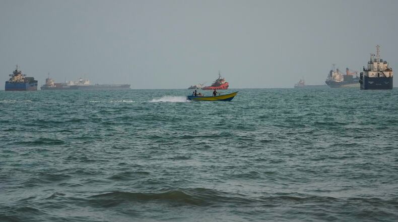 A swimmer remains near the shore as a motorboat passes commercial vessels anchored in the Strait of Hormuz off Bandar Abbas, Iran, Friday, Sept. 4, 2026. (AP Photo/Vahid Salemi)