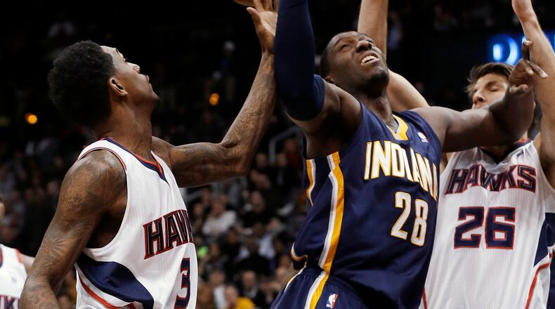 Indiana Pacers center Ian Mahinmi (28) reaches for a rebound between Atlanta Hawks' Kyle Korver (26) and Louis Williams during the first half of an NBA basketball on Wednesday, Jan. 8, 2014, in Atlanta. The Hawks won, 97-87 (AP Photo/John Bazemore)