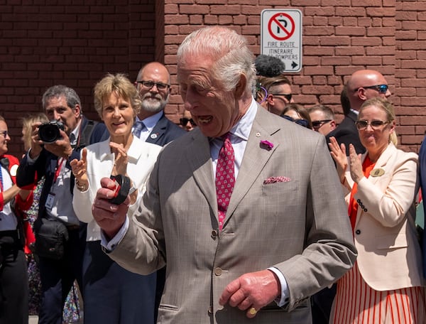 King Charles looks at the puck after participating in a ceremonial puck drop during a visit to Lansdowne Park in Ottawa, Canada, on Monday, May 26, 2025. (Christinne Muschi/The Canadian Press via AP)