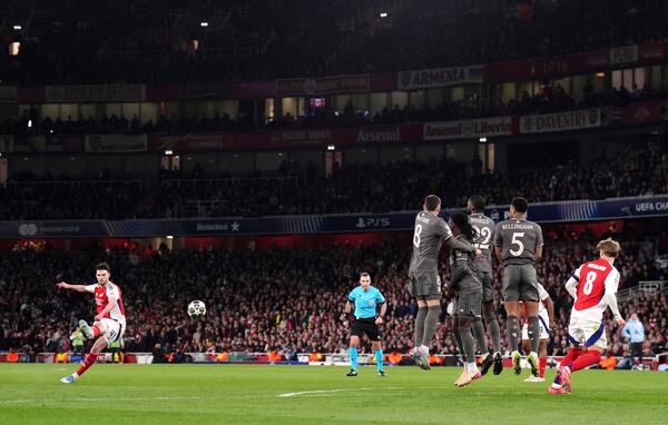 Arsenal's Declan Rice, left, scores his side's opening goal during the Champions League quarterfinal first leg soccer match between Arsenal and Real Madrid at the Emirates Stadium in London, Tuesday, April 8, 2025. (John Walton/PA via AP)