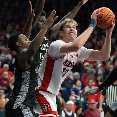 Arizona center Motiejus Krivas scores in between Cincinnati guard Grant Darbyshire (13), guard Sencire Harris (5), and forward Baba Miller during the second half of an NCAA college basketball game, Wednesday, Jan. 21, 2026, in Tucson, Ariz. (AP Photo/Rick Scuteri)