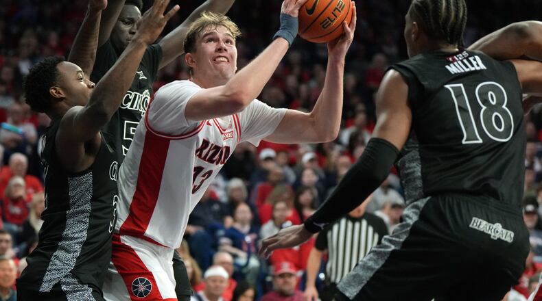 Arizona center Motiejus Krivas scores in between Cincinnati guard Grant Darbyshire (13), guard Sencire Harris (5), and forward Baba Miller during the second half of an NCAA college basketball game, Wednesday, Jan. 21, 2026, in Tucson, Ariz. (AP Photo/Rick Scuteri)