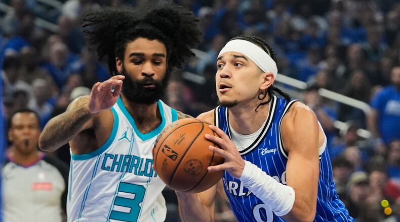 Orlando Magic guard Anthony Black (0) drives around Charlotte Hornets guard Coby White (3) during the first half of an NBA play-in tournament basketball game, Friday, April 17, 2026, in Orlando, Fla. (AP Photo/John Raoux)