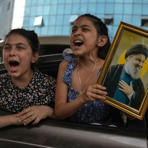 Two girls chant slogans as one holds an image of the late Hezbollah leader Hassan Nasrallah in Dahiyeh, Beirut's southern suburbs, Lebanon, Friday, April 17, 2026, following a ceasefire between Israel and Hezbollah. (AP Photo/Bilal Hussein)