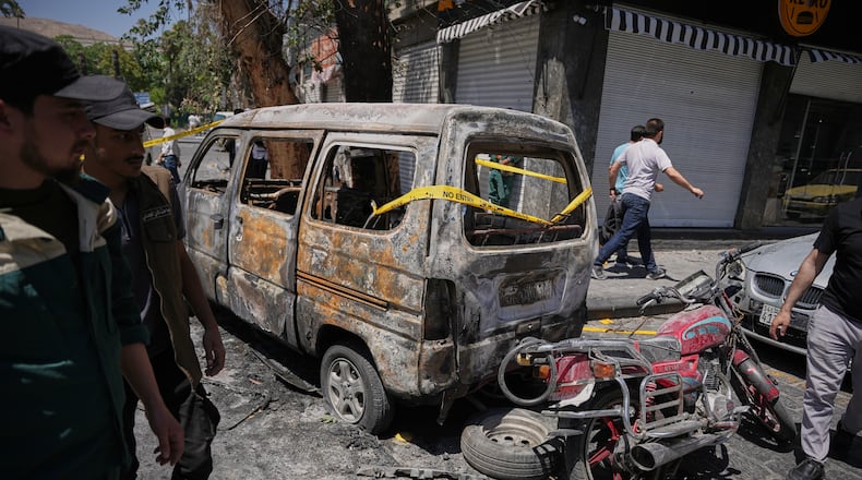Syrian security personnel inspect a burned vehicles near the Four Seasons Hotel after two explosions rocked the area earlier while Syrian President Ahmad al-Sharaa was meeting French President Emmanuel Macron at the presidential palace, in Damascus, Syria, Tuesday, July 7, 2026. (AP Photo/Omar Albam)