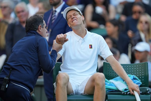 Italy's Jannik Sinner grimaces as he receives medical treatment against Bulgaria's Grigor Dimitrov during a fourth round men's singles match at the Wimbledon Tennis Championships in London, Monday, July 7, 2025. (AP Photo/Kin Cheung)