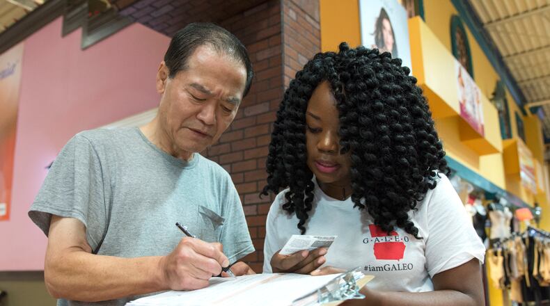 Victoria Arzu, 28, right, of Lawrenceville, helps Gold Pak, 66, left, from Doraville register to vote in Gwinnett County in this file photo from October. David Barnes, david.barnes@ajc.com