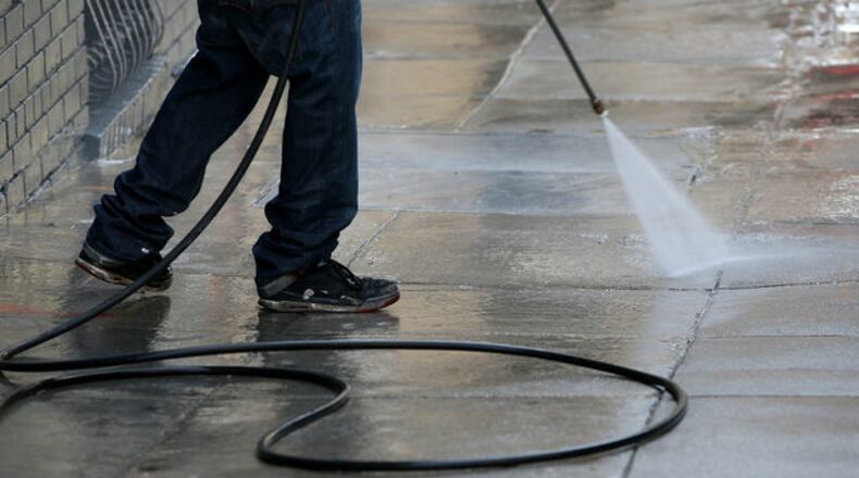 A worker uses a pressure washer to clean the sidewalk in front of a building on May 6, 2015 in San Francisco, California.