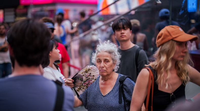 FILE - A person uses a fan as they wait in line to purchase Broadway tickets in Times Square, during a heat advisory in New York, May 19, 2026. (AP Photo/Adam Gray, File)