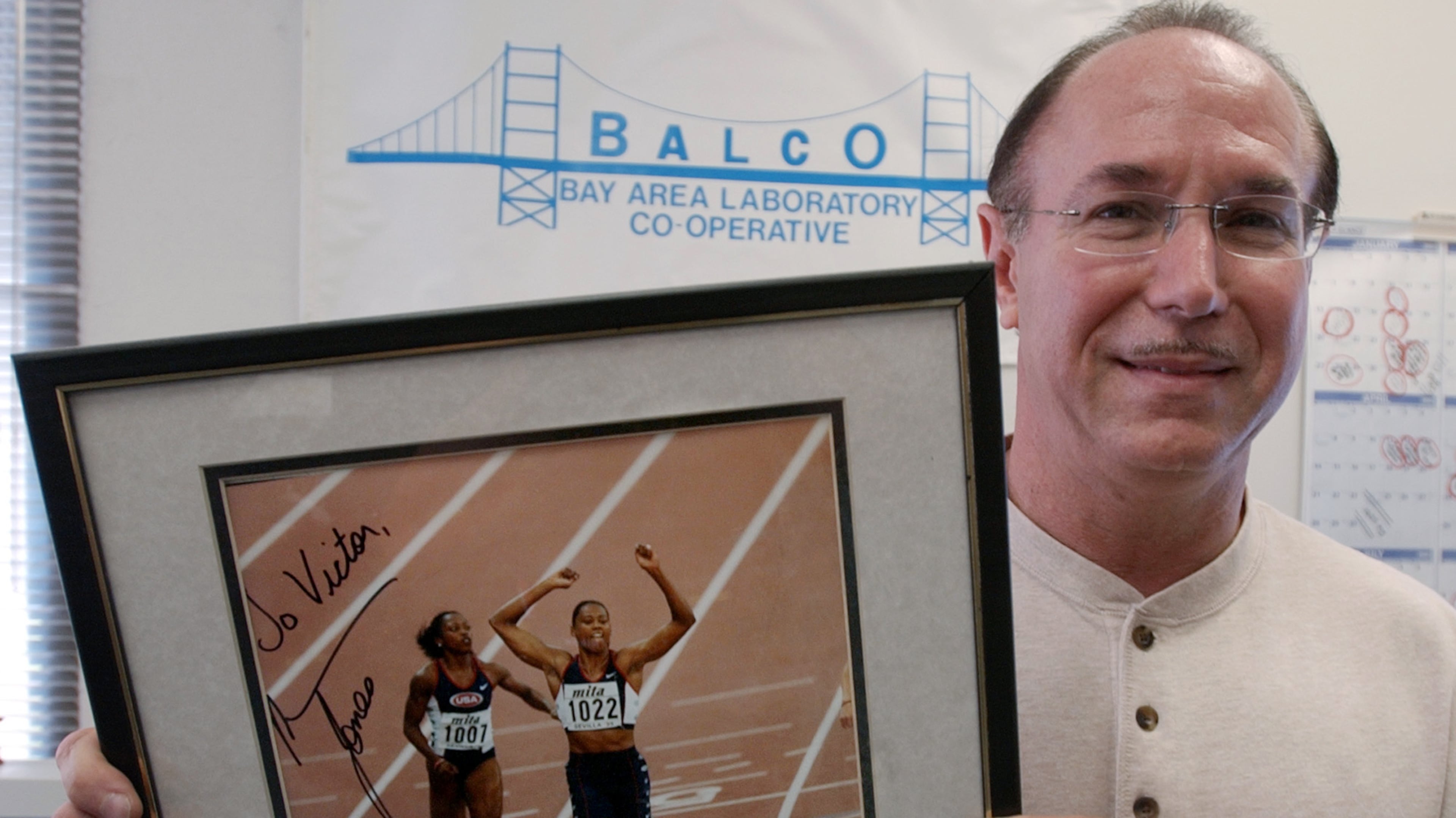 FILE - BALCO founder Victor Conte holds up an autographed photo addressed to Conte of track star Marion Jones in his office in Burlingame, Calif., Oct. 21, 2003. (AP Photo/Paul Sakuma, File)