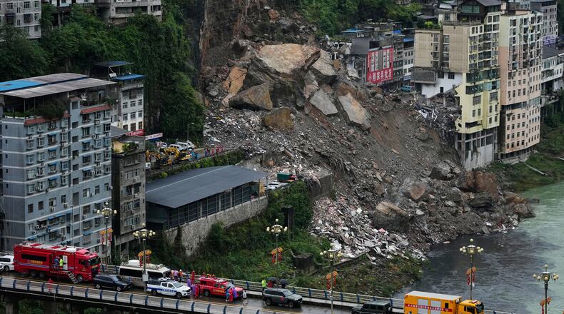 Rescuers stand by along the bridge as they prepare to conduct a search and rescue operation at the scene of a landslide in Pengshui County in southwestern China's Chongqing on Saturday, July 18, 2026. (AP Photo/Andy Wong)