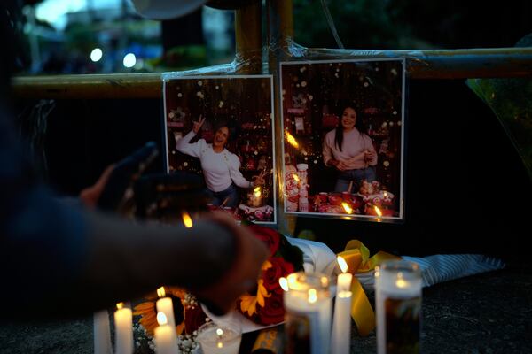 A person lights a candle at a makeshift memorial outside the Jet Set nightclub, in memory of the more than 200 people who died when its roof collapsed, in Santo Domingo, Dominican Republic, Friday, April 11, 2025. (AP Photo/Matias Delacroix)