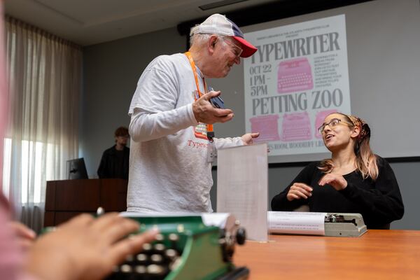 Tom Rehkopf, 82, speaks to Madeline Rommer at a “typewriter petting zoo” event at Emory University’s Woodruff Library on October 22, 2025. Rehkopf has collected around 1,000 typewriters. (Arvin Temkar / AJC)