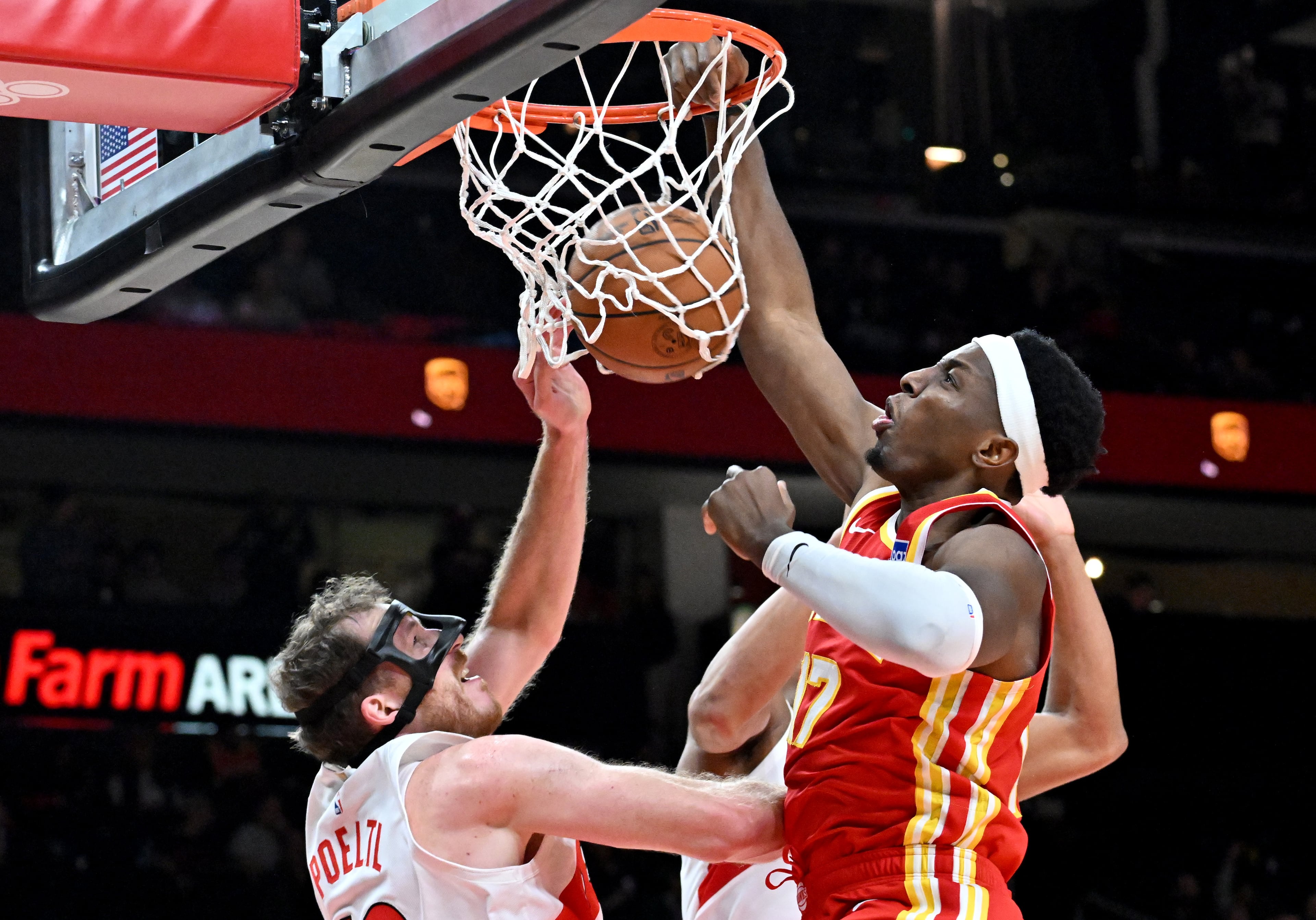 Atlanta Hawks forward/center Onyeka Okongwu (17) dunks the ball against Toronto Raptors center Jakob Poeltl (19) during the second half in the home opener at State Farm Arena, Thursday, October 22, 2025, in Atlanta. Toronto Raptors won 138-118 over Atlanta Hawks. (Hyosub Shin / AJC)
