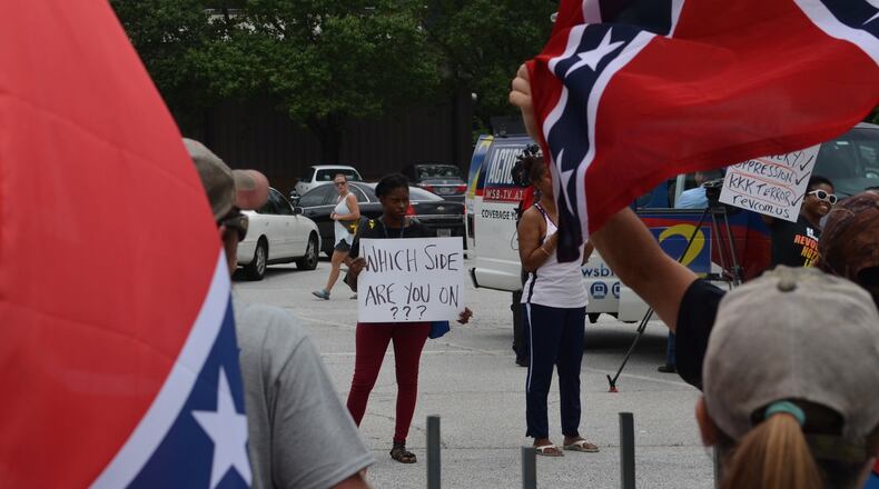 A counter-protestor peacefully holds up a sign before a verbal dispute broke out on the other side of the Yellow Daisy parking lot at Stone Mountain on Saturday, August 1, 2015. DANIEL FUNKE / DANIEL.FUNKE@COXINC.COM