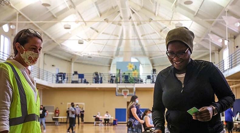 Cobb County Poll Clerk Andrea Keener (left) assists Smyrna resident Qris Dorvil as she places her ballot in the electronic ballot machine at the Smyrna Community Center.