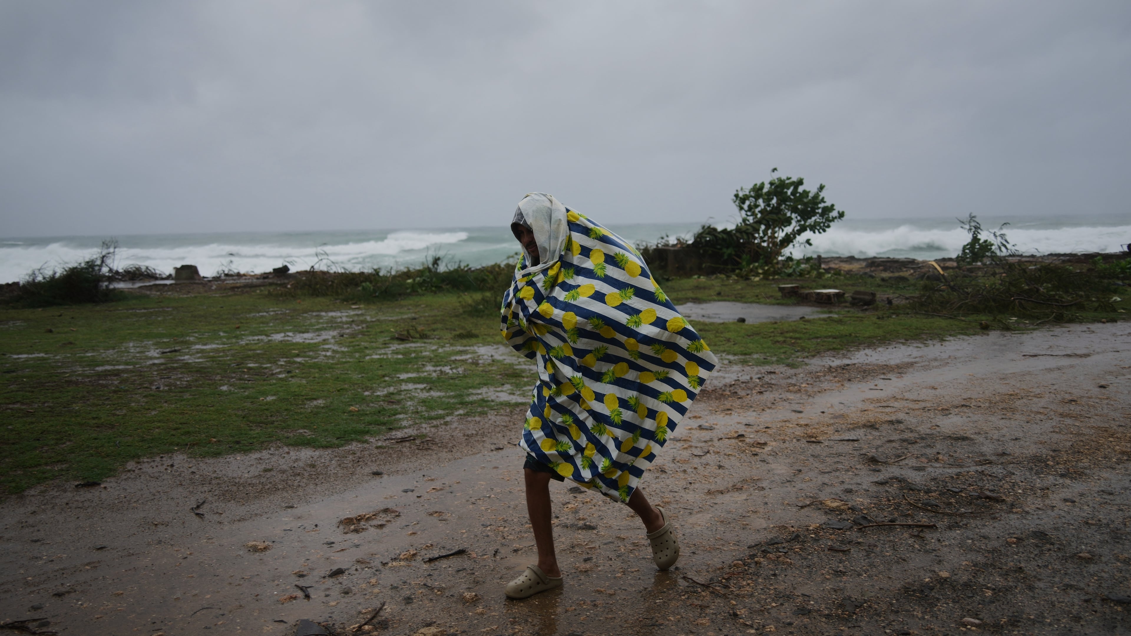 A man walks in the rain before the arrival of Hurricane Melissa in Canizo, a village in Santiago de Cuba, Tuesday, Oct. 28, 2025. (AP Photo/Ramón Espinosa)