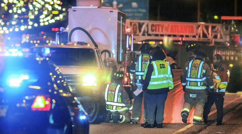 Firefighters and investigators at the scene of a horrific accident before dawn Monday in which a man jumped from an ambulance on the Downtown Connector, ran out into traffic and was struck and killed. John Spink / jspink@ajc.com