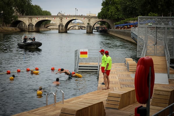 A swimmer dives in the water as people swim at the Pont Marie safe bathing site on the Seine river in Paris, France, Saturday, July 5, 2025, during the opening of the three Seine swimming pools, as part of the 'Paris Plages' event. (AP Photo/Thomas Padilla)
