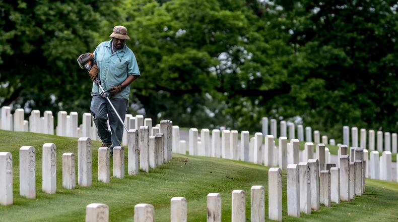 Greg Weber trims along the rows of headstones at the Marietta National Cemetery, located at 500 Washington Avenue in Marietta, on Thursday in preparation for Memorial Day weekend. (John Spink/AJC)