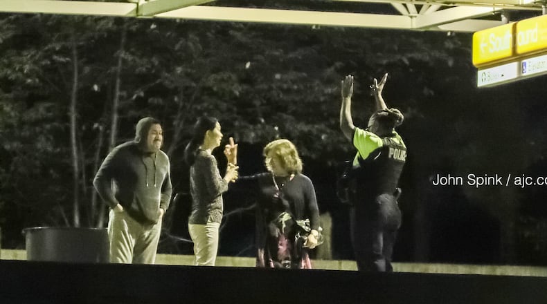 A MARTA police officer directs passengers on the train deck of the Chamblee station after an emergency suspended rail service Tuesday morning.