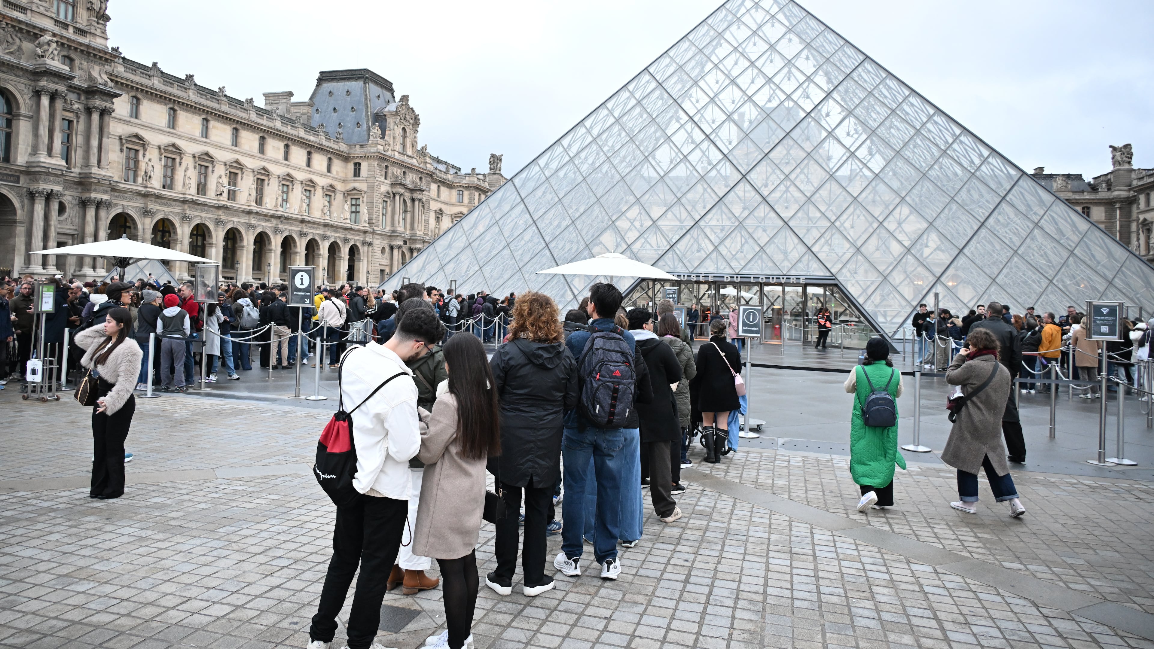 People queue outside the Louvre museum in Paris on Monday, Oct. 20, 2025, although it remains closed for the day after Sunday's jewels robbery. (AP Photo/Emma Da Silva)