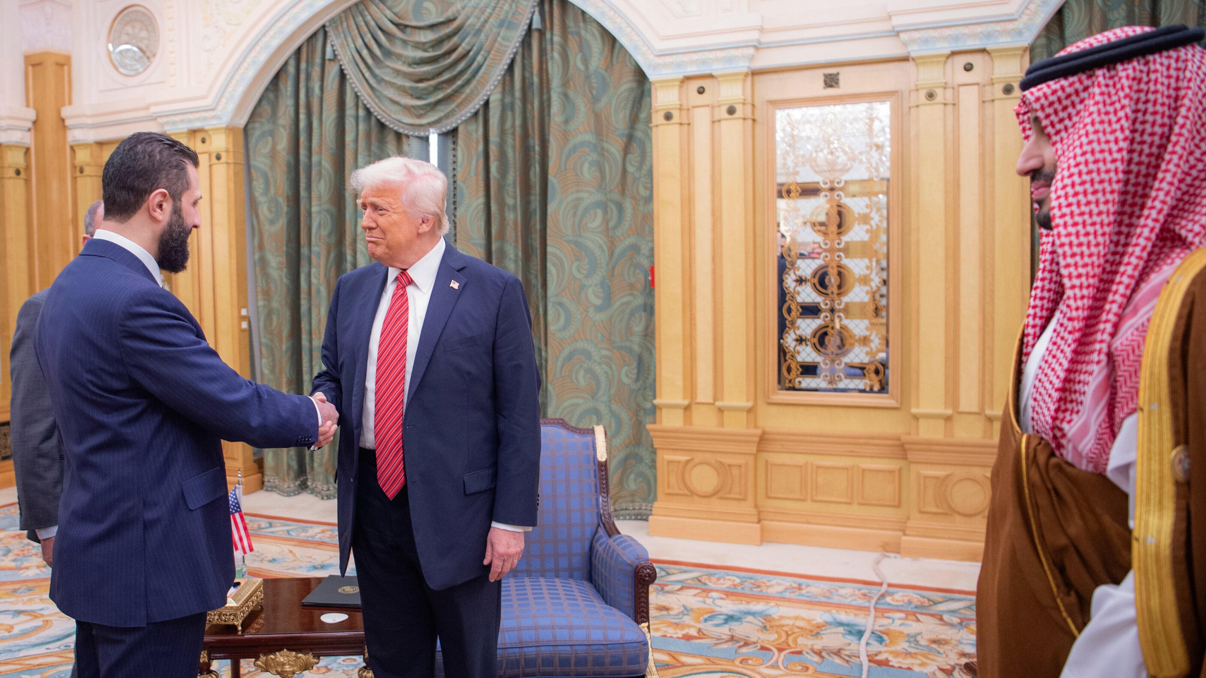 FILE - In this photo provided by the Saudi Royal Palace, Syria's interim President Ahmad al-Sharaa, left, shakes hands with U.S. President Donald Trump in Riyadh, Saudi Arabia, Wednesday, May 14, 2025. At foreground right is Saudi Crown Prince Mohammed bin Salman. (Bandar Aljaloud/Saudi Royal Palace via AP, File)