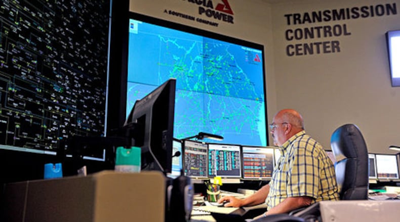 Gerald Snodgrass sits in front of the large electronic mimic board (left), which displays the status of transmission lines and substations around the state, and a smaller screen (right) which shows the Southern Company load flow from Mississippi to the Florida panhandle, at the Georgia Transmission Control Center at Georgia Power.