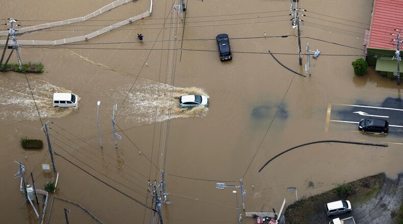 Cars make their way through flooded road after heavy rain in Oamishirasato, Chiba prefecture, Japan, Friday, Aug. 14, 2026. (Kota Endo/Kyodo News via AP)