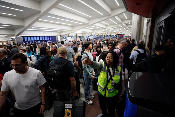An airport agent assists travelers with the long lines early Monday morning at Hartsfield-Jackson Atlanta International Airport. (Miguel Martinez/AJC)