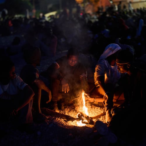 Migrants who crossed into Spain from Morocco gather around a bonfire on a beach in the Spanish enclave of Ceuta, Sunday, Aug. 2, 2026. (AP Photo/Bernat Armangue)