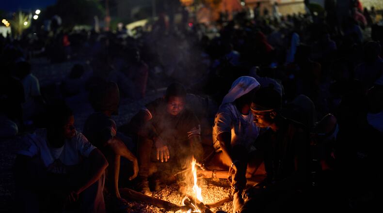Migrants who crossed into Spain from Morocco gather around a bonfire on a beach in the Spanish enclave of Ceuta, Sunday, Aug. 2, 2026. (AP Photo/Bernat Armangue)