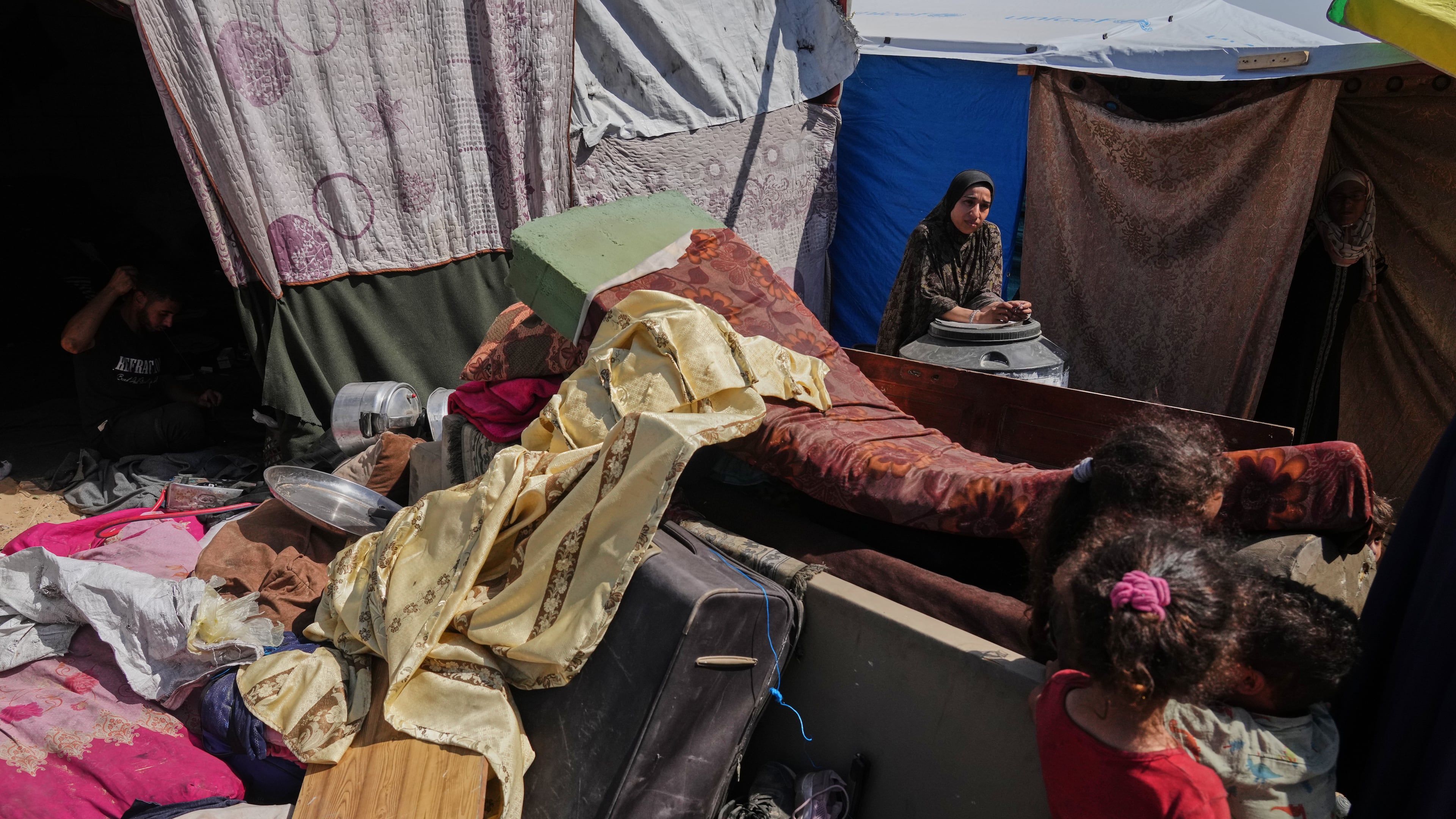 A woman stands beside her belongings after arriving from northern Gaza to a camp for displaced Palestinians in Muwasi, an area that Israel has designated as a safe zone, in Khan Younis southern Gaza Strip, Monday, Sept. 29, 2025. (AP Photo/Jehad Alshrafi).