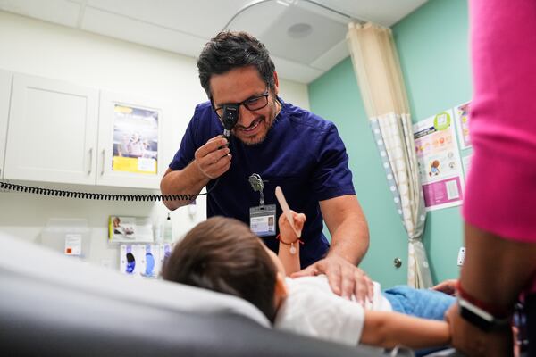 Pediatrician Irving Phillips, left, examines a 16-month-old boy at a CommuniCARE+OLE clinic Thursday, June 26, 2025, in Davis, Calif. (AP Photo/Godofredo A. Vásquez)