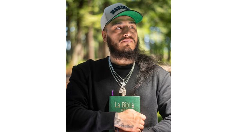 Gabriel Martinez Garcia, 30, holds a Bible close to his chest as tattoos of his parents are visible on his wrists, in Tenino, Wash., on Sunday, June 14, 2026. (AP Photo/Akash Pamarthy)