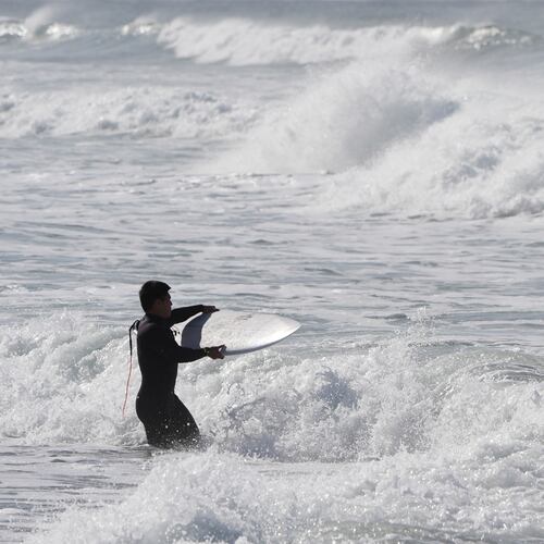 A surfer enters the water after a rainstorm at Cardiff State Beach Friday, Nov. 21, 2025, in Solana Beach, Calif. (AP Photo/Gregory Bull)