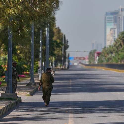 An army soldier, left, walks as police officer drives motorcycle on an empty road ahead of second round of negotiations between the U.S. and Iran, in Islamabad, Pakistan, Monday, April 20, 2026. (AP Photo/Anjum Naveed)