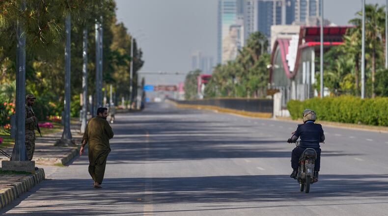An army soldier, left, walks as police officer drives motorcycle on an empty road ahead of second round of negotiations between the U.S. and Iran, in Islamabad, Pakistan, Monday, April 20, 2026. (AP Photo/Anjum Naveed)