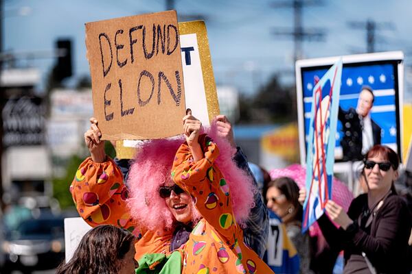 FILE - Vanessa Gonzalez joins other protesters carrying signs and chanting slogans outside a Tesla showroom and service center in the North Hollywood section of Los Angeles, March 15, 2025. (AP Photo/Richard Vogel, File)